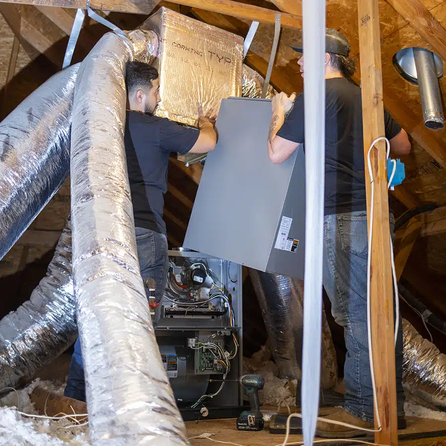 Two Torch Plumbing, Heating, & Cooling technicians installing furnace system in Owasso home.