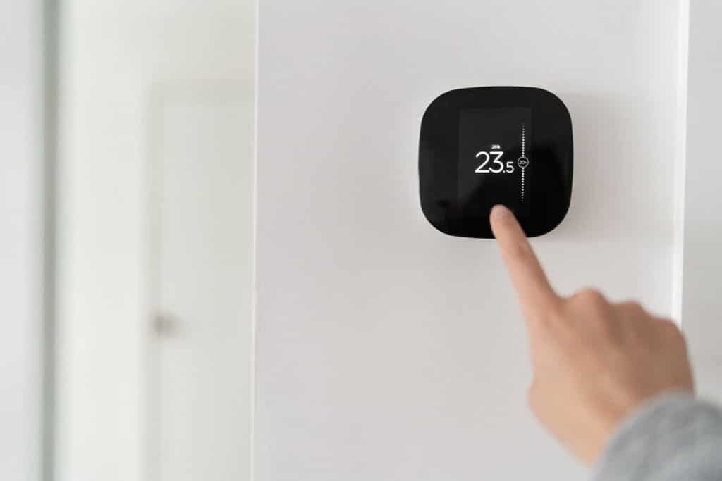 person adjusting smart thermostat